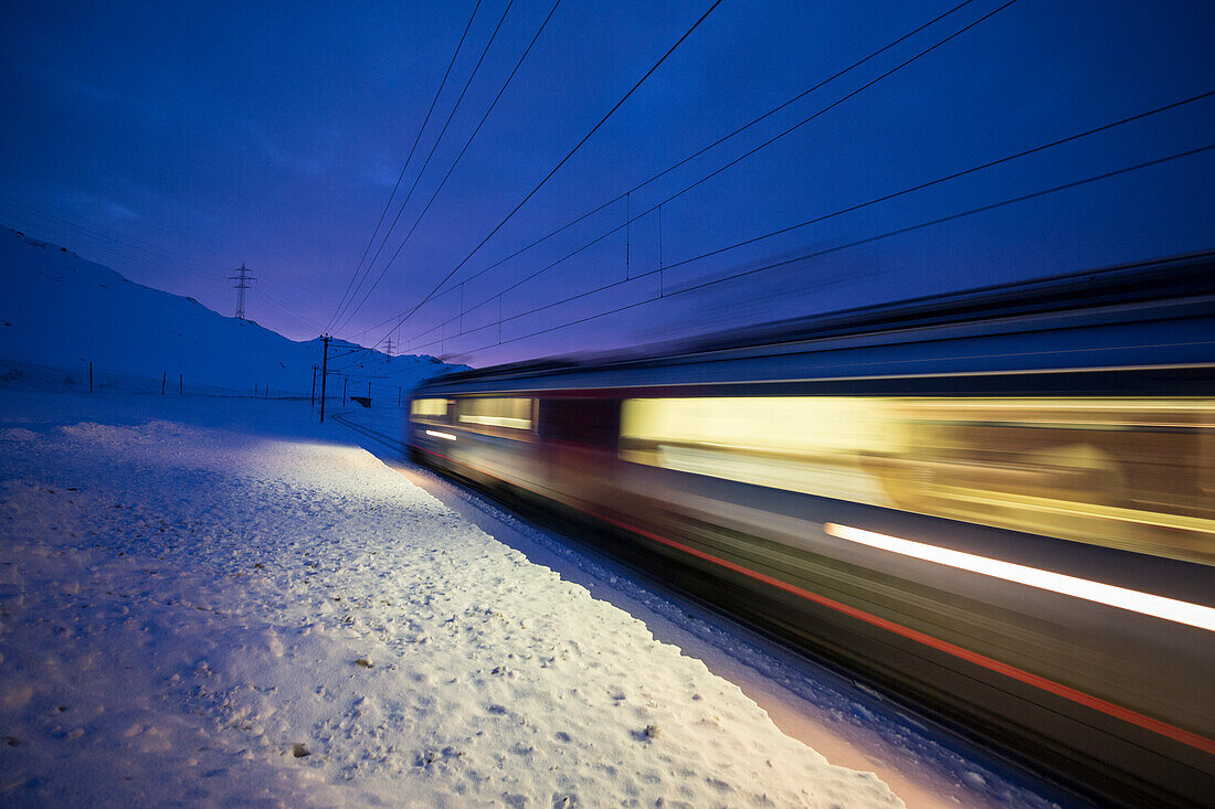 Bernina Express Zug fährt schnell in der verschneiten Landschaft in der Dämmerung Bernina Pass Kanton Graubünden Engadin Schweiz Europa