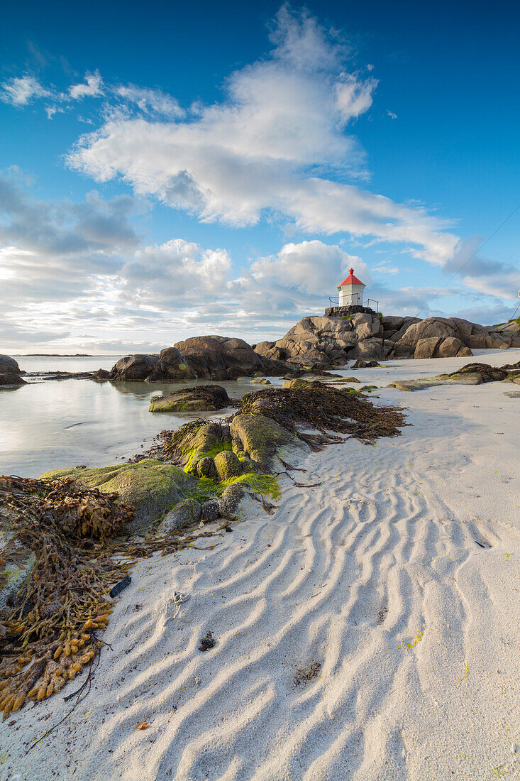 Mitternachtssonne leuchtet Leuchtturm auf Klippen, umgeben von Meer und Sand Eggum Unstad Vestvagøy Lofoten Inseln Norwegen Europa