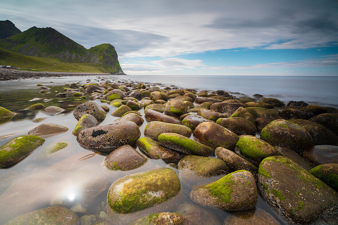 Rocks on the beach frame the calm clear sea Unstad Vestvagøy Lofoten Islands Norway Europe