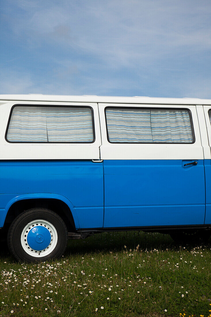 Seitenansicht der blauen und weißen Van geparkt auf Gras am Strand