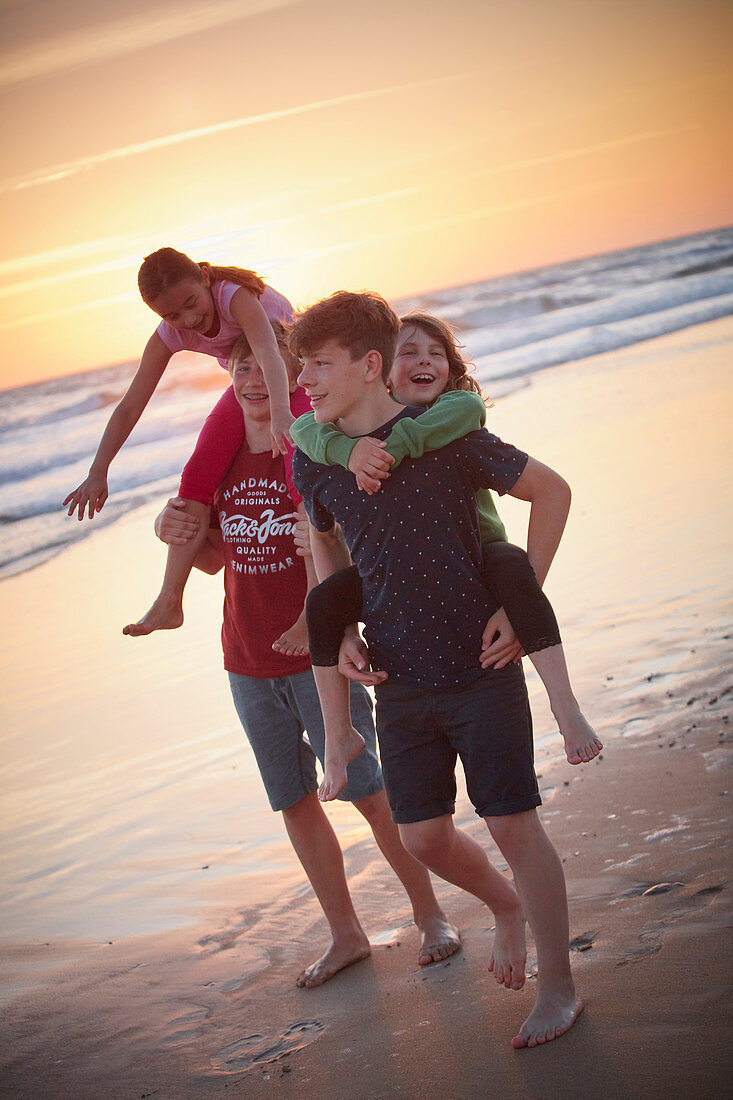2 girls getting carried by their brothers on the beach,  roche beach, andalusia, southwest coast spain, atlantc, Europe