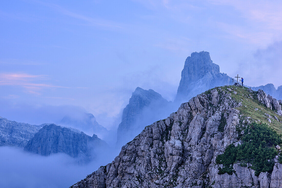Person steht auf Berggipfel und fotografiert, Felszacken und Wolken im Hintergrund, Croz dell' Altissimo, Brentagruppe, UNESCO Welterbe Dolomiten, Trentino, Italien