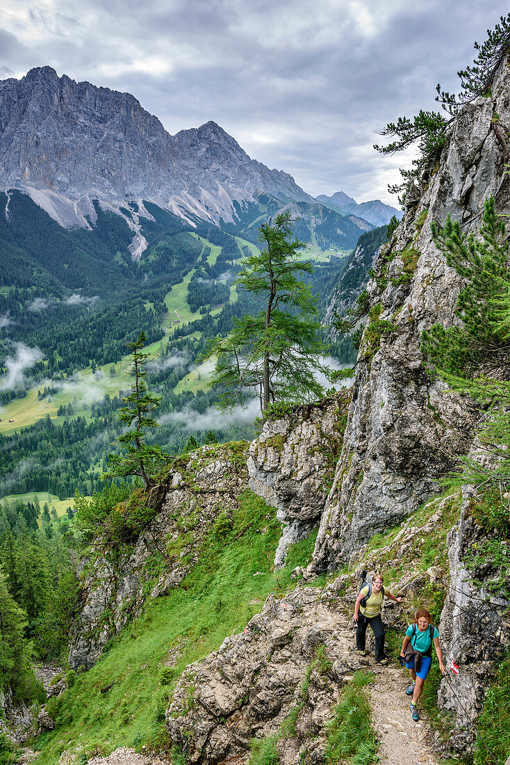 Two women hiking ascending towards hut Coburger Huette, Hoher Gang, Mieming Mountains, Tyrol, Austria