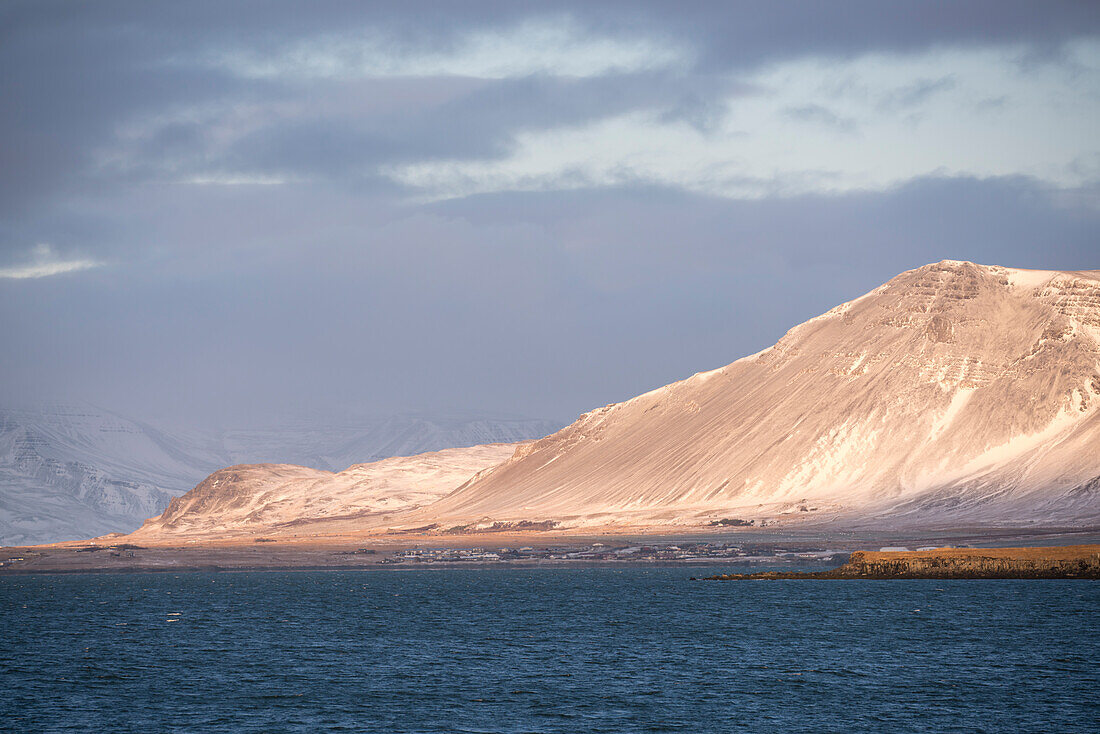 Verschneite Landschaft an der Küste von Reykjavík mit Blick auf das Gebirge Esja in Wolken, Reykjavik, Island, Iceland, Europa