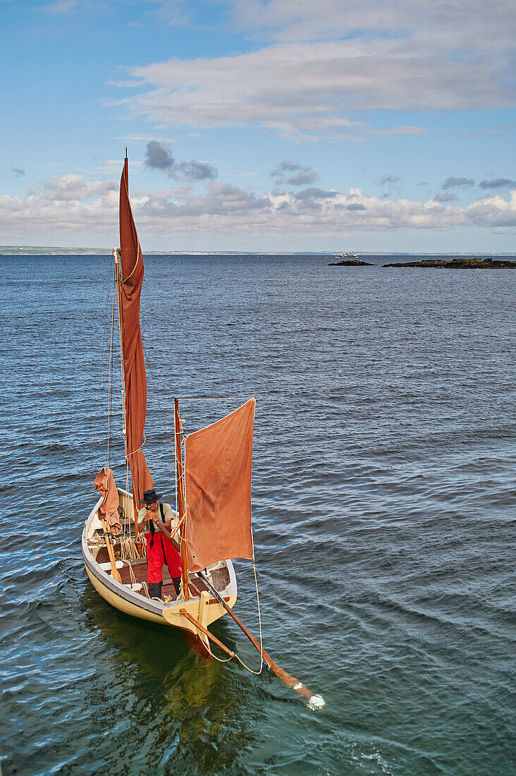 A fisherman sets out in his oyster dredger from Mousehole Harbour, Penwith, Cornwall, England, United Kingdom, Europe