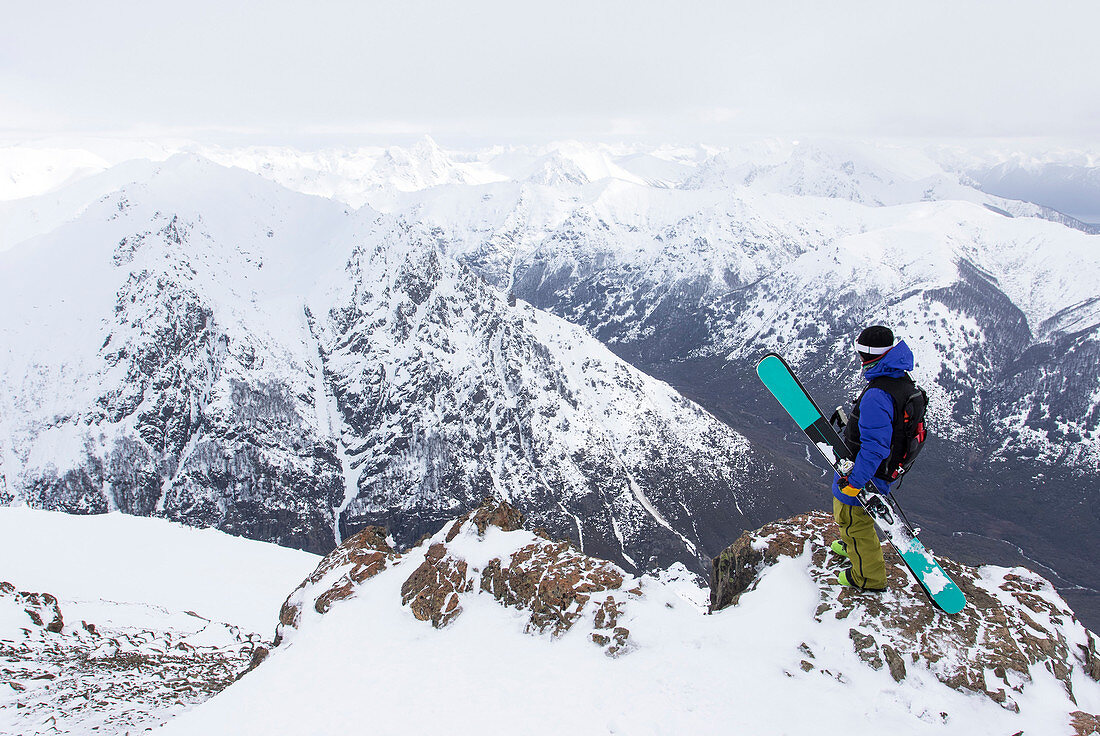 Ein Skifahrer steht auf einem felsigen Berg mit Blick auf die Anden von Cerro Catedral In Argentinien