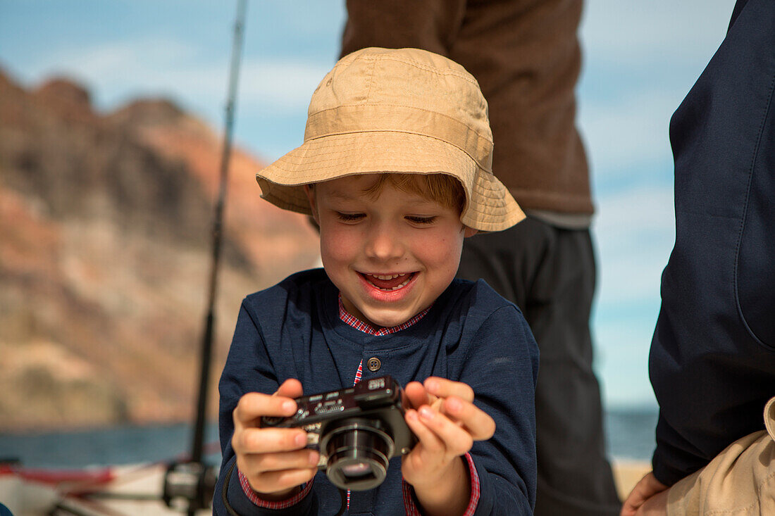 Young boy looks through camera on boat