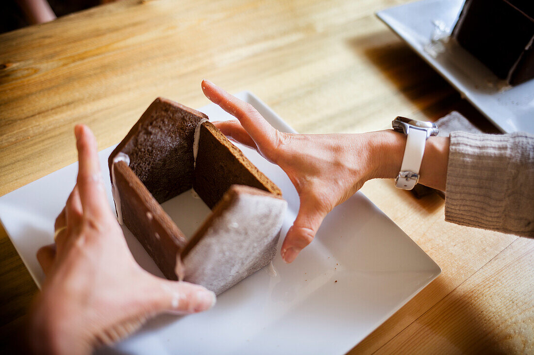 Loving hands of a mother make a Gingerbread house at Christmastime.