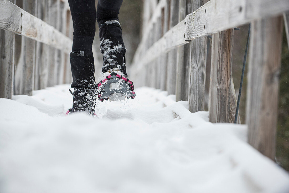 Person Schneeschuhwandern auf Fußgängerbrücke im Winter