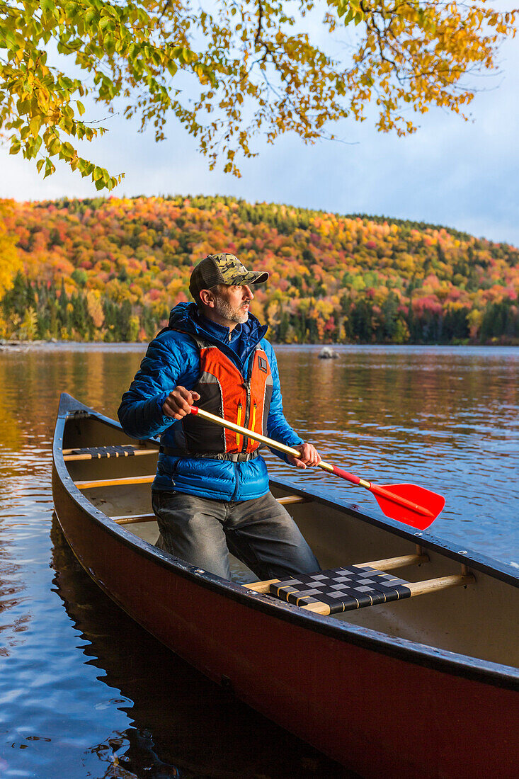 Ein Mann Kanu auf Greenough Teich im Herbst bei Wentworths Lage, New Hampshire