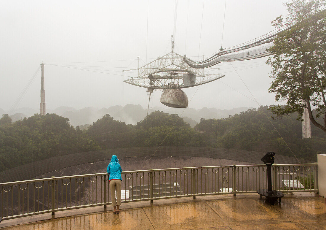 A woman stands next to the world's largest satellite dish at Arecibo Observatory in Puerto Rico.