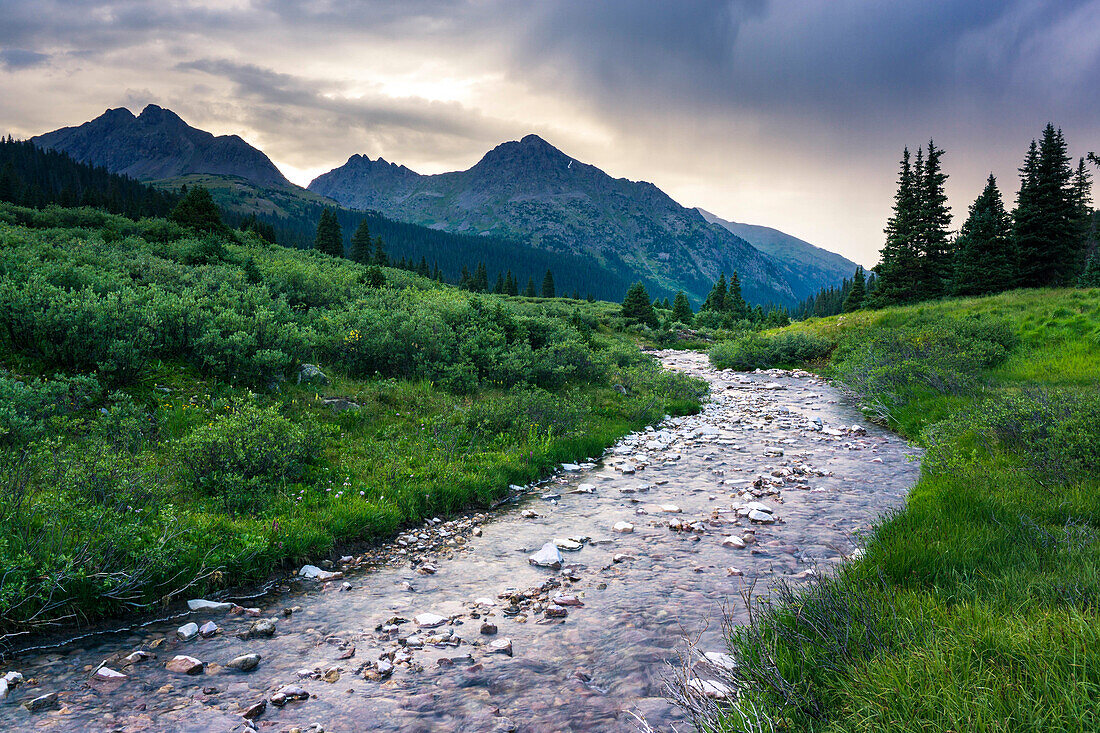 Colorado mountain scene with a river and mountains after a thunderstorm during sunset