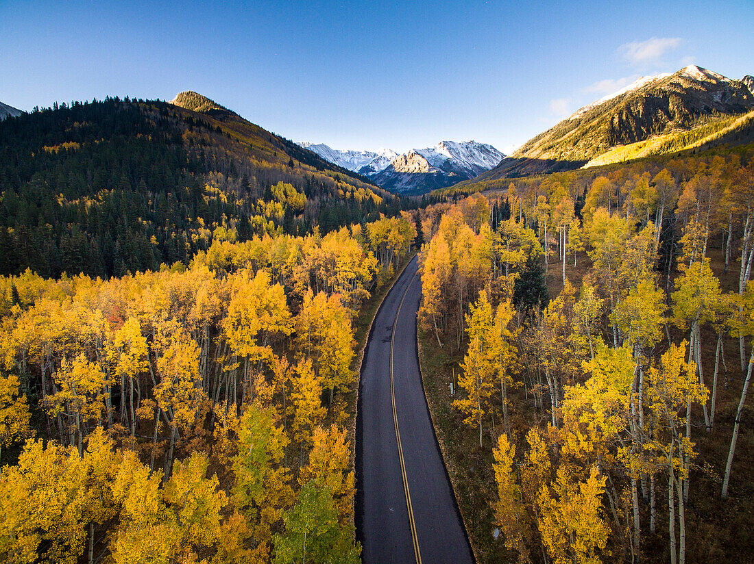Aerial view of fall colors and a road in Aspen Colorado with a fresh dusting of snow