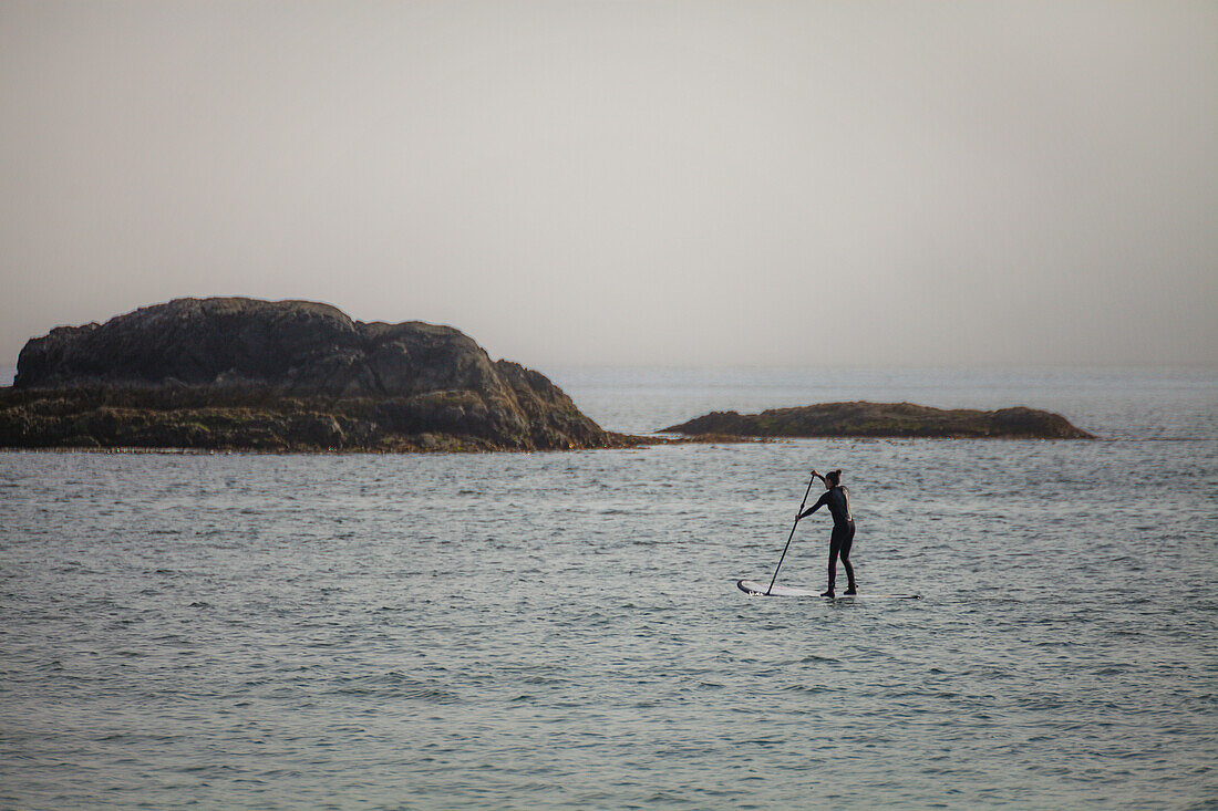 A young woman paddles a SUP in Pacific Rim National Park, Vancouver Island, British Columbia