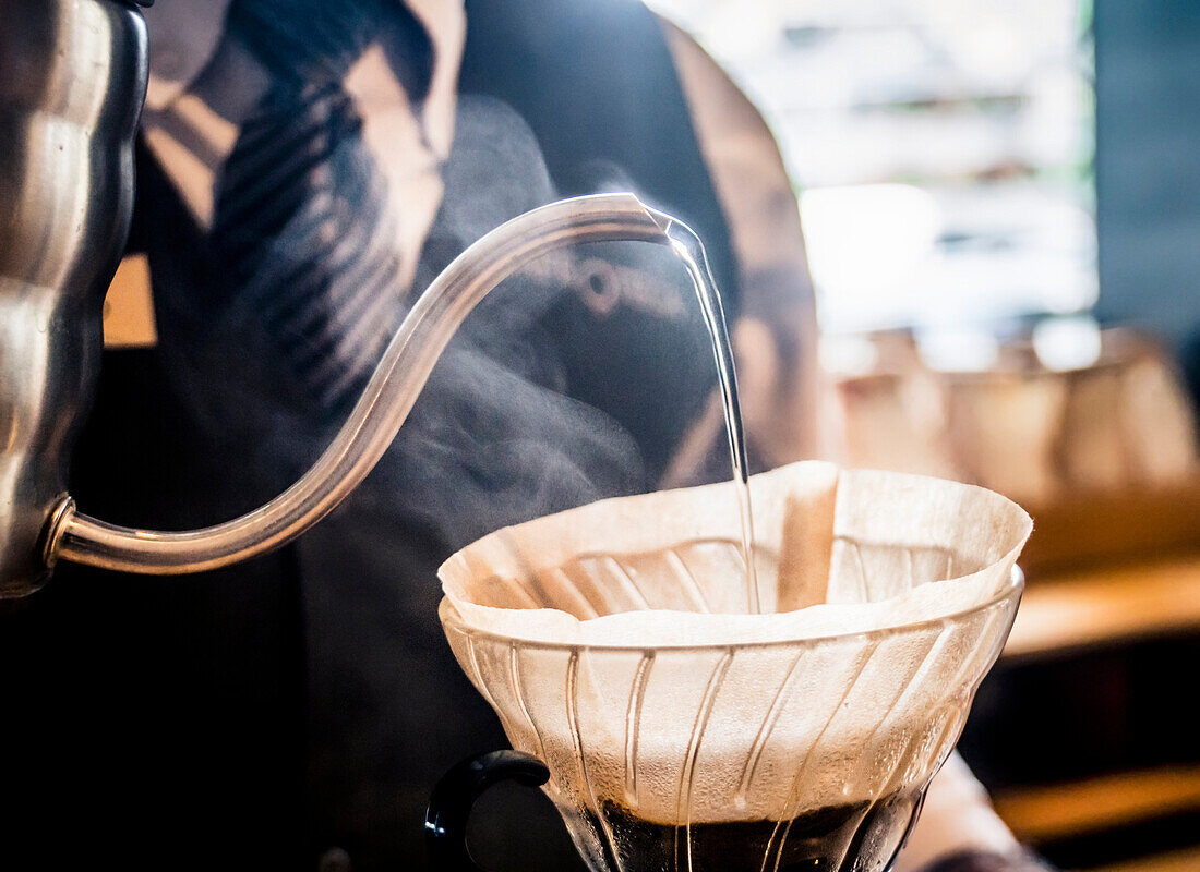 Ein Barista gießt heißes Wasser über handwerkliche Kaffeebohnen in einem Café in San José, Costa Rica