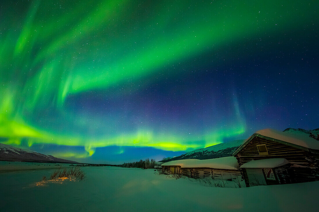 'Die Aurora füllt den Himmel über dem historischen Black Rapids Roadhouse entlang der Richardson Highway auf einer bitterkalten Nacht; Alaska, Vereinigte Staaten von Amerika'