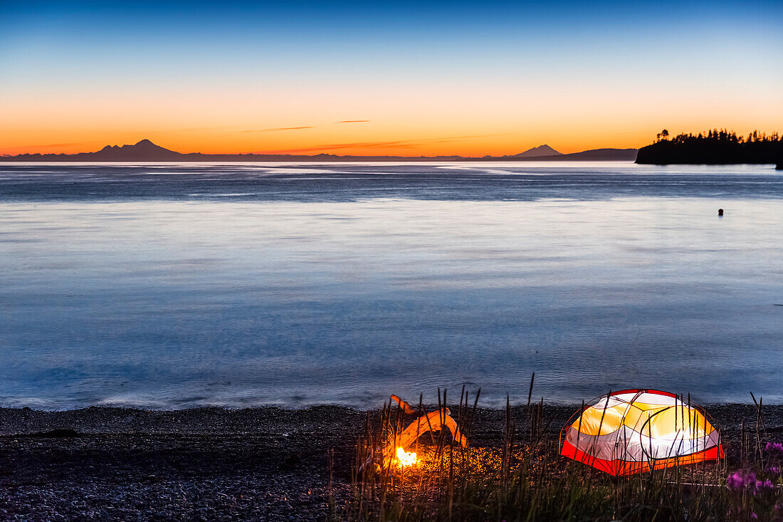 Lit Zelt und Lagerfeuer am Strand in der Dämmerung, Hesketh Island, Homer, South Central Alaska, USA