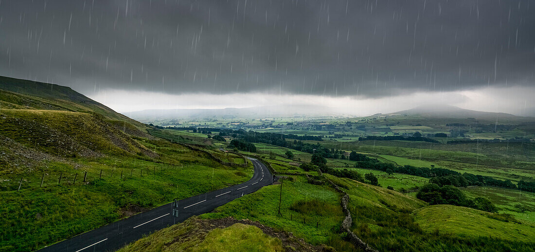 'Rain falling from a stormy sky over a lush, green landscape; North Yorkshire, England'