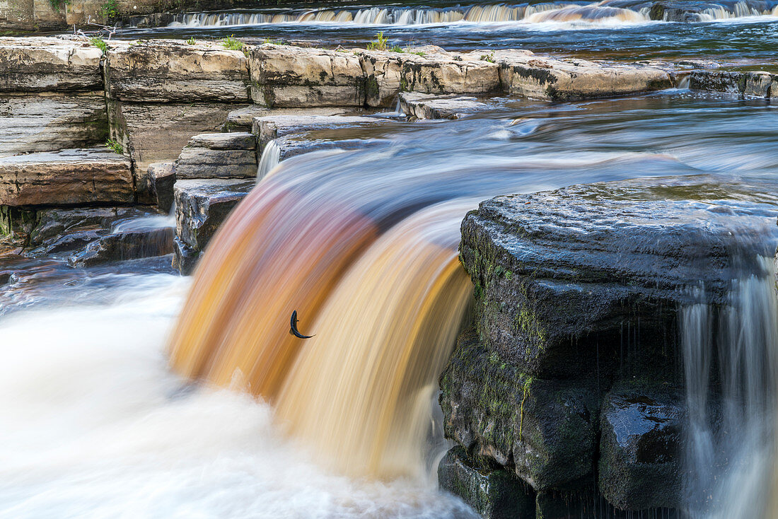 'Farbiger Wasserfall fließt über eine Klippe; Richmond, North Yorkshire, England'