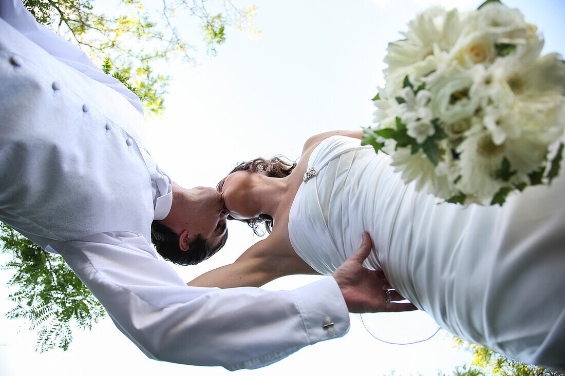 'Low angle view of a bride and groom kissing on the wedding day; Ontario, Canada'