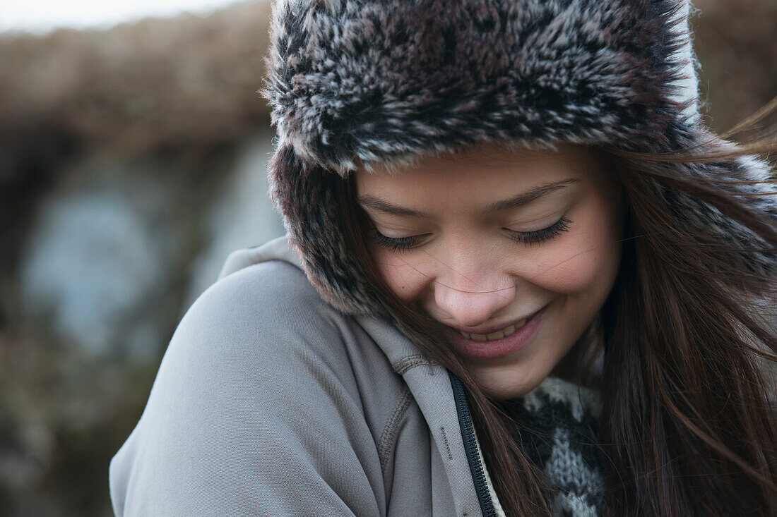 'Portrait Of A Young Woman Wearing A Fur Trimmed Hat And Looking Down; Iceland'