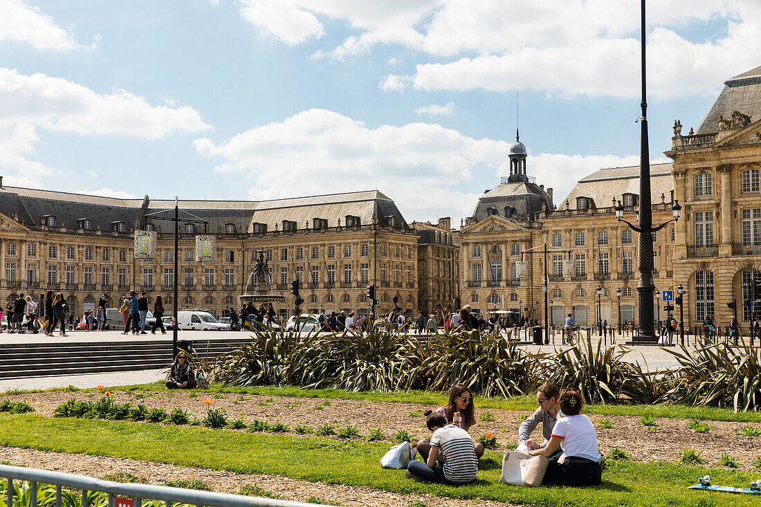 Place de la Bourse mit jungen Menschen die im Gras sitzen, Bordeaux, Gironde, Nouvelle-Aquitaine, Frankreich, Europa