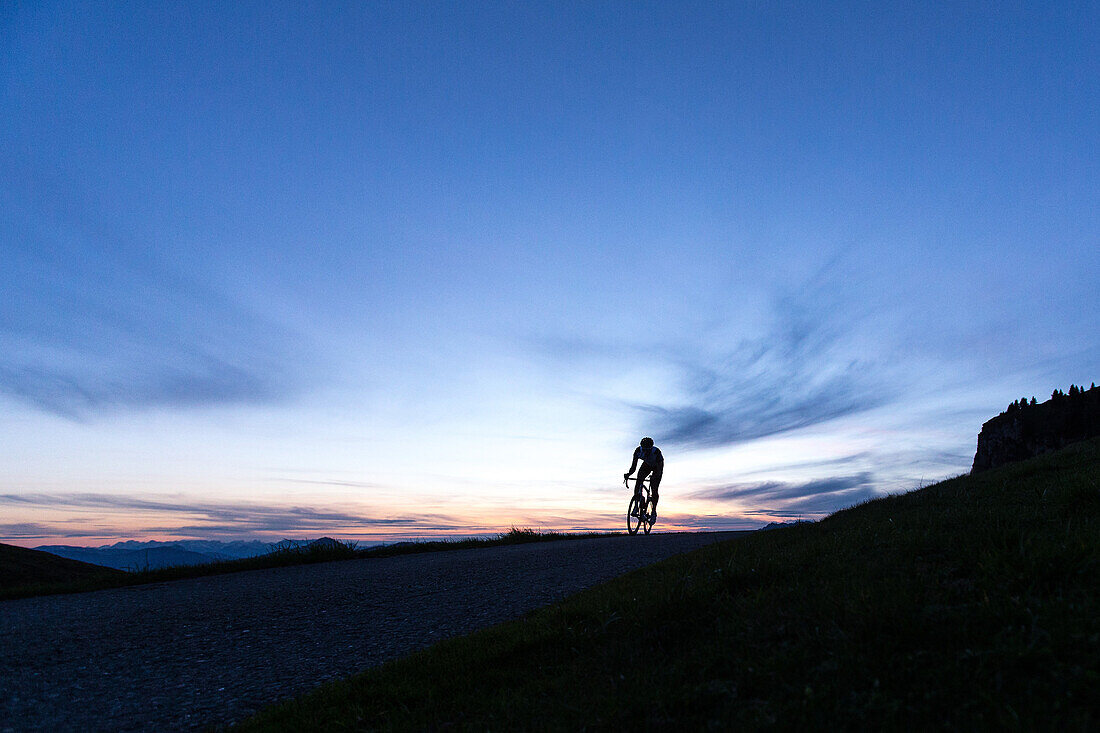 Young man on his racing cycle while sunset at the Kitzbühler Alps, Kitzbühlerhorn, Tyrol, Austria