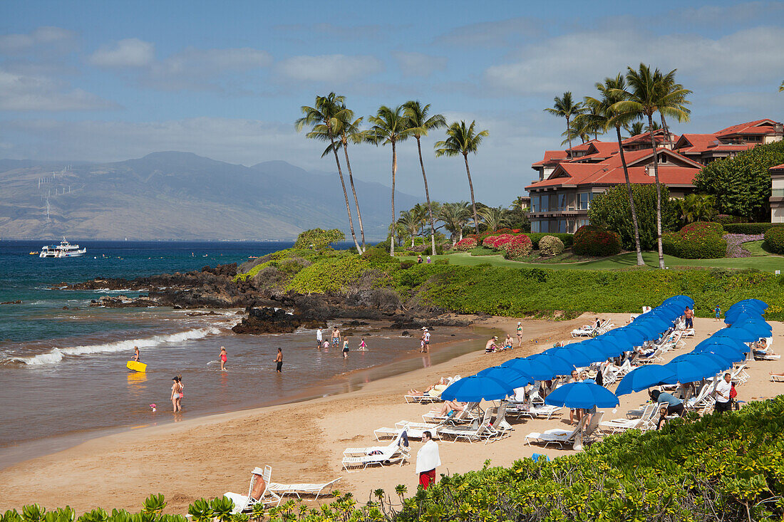 'Beach umbrellas on Polo Beach and a snorkel boat off the shore; Wailea, Maui, Hawaii, United States of America'