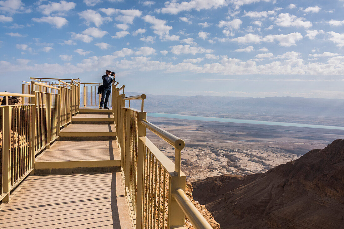 'A tourist stands at the end of a lookout with a view of the Dead Sea region and the desert; South District, Israel'