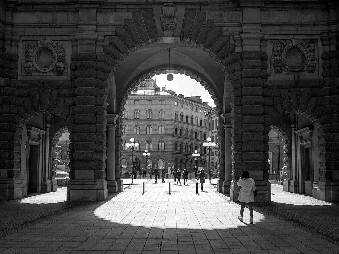 'Pedestrians walking on the street and through and archway in old town, Gamla Stan; Stockholm, Sweden'