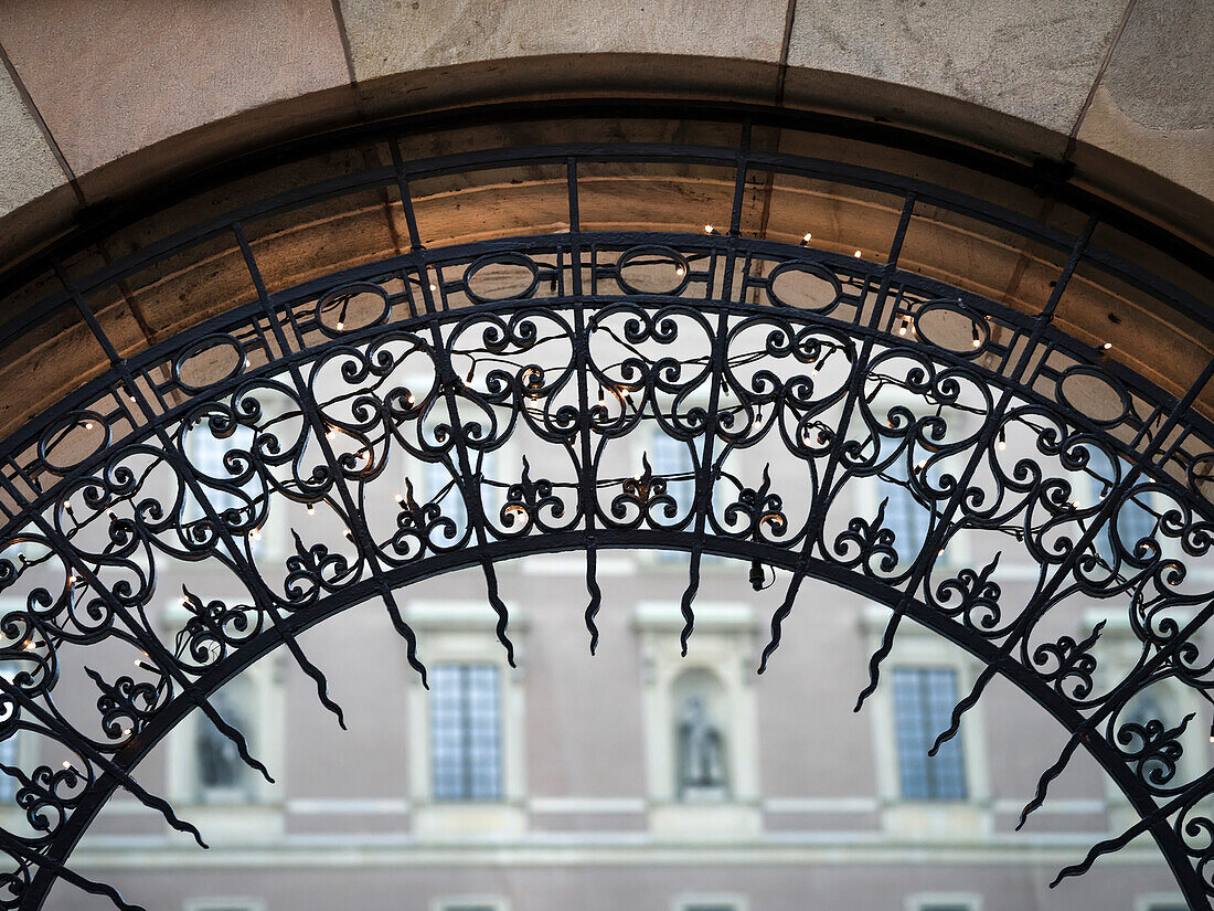 Nahaufnahme des kunstvollen Designs auf einem Torbogen mit einem Gebäude im Hintergrund, Stockholm, Schweden