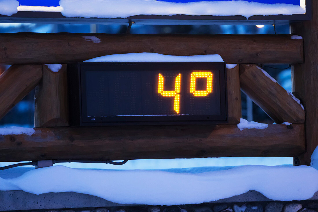An outdoor digital thermometer in the snow in winter measuring four degrees fahrenheit, Alaska, United States of America