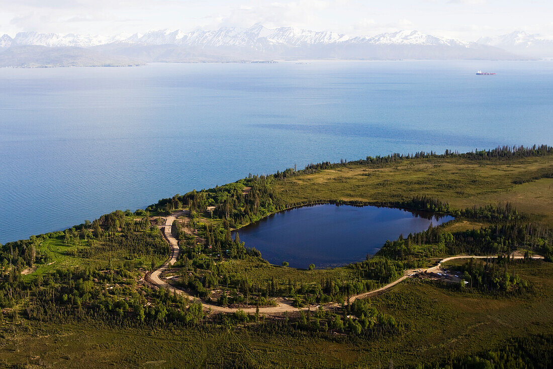 A lake and winding road off Kachemak Bay with a view of the Kenai Mountains, Kachemak Bay State Park, Homer, Alaska, United States of America