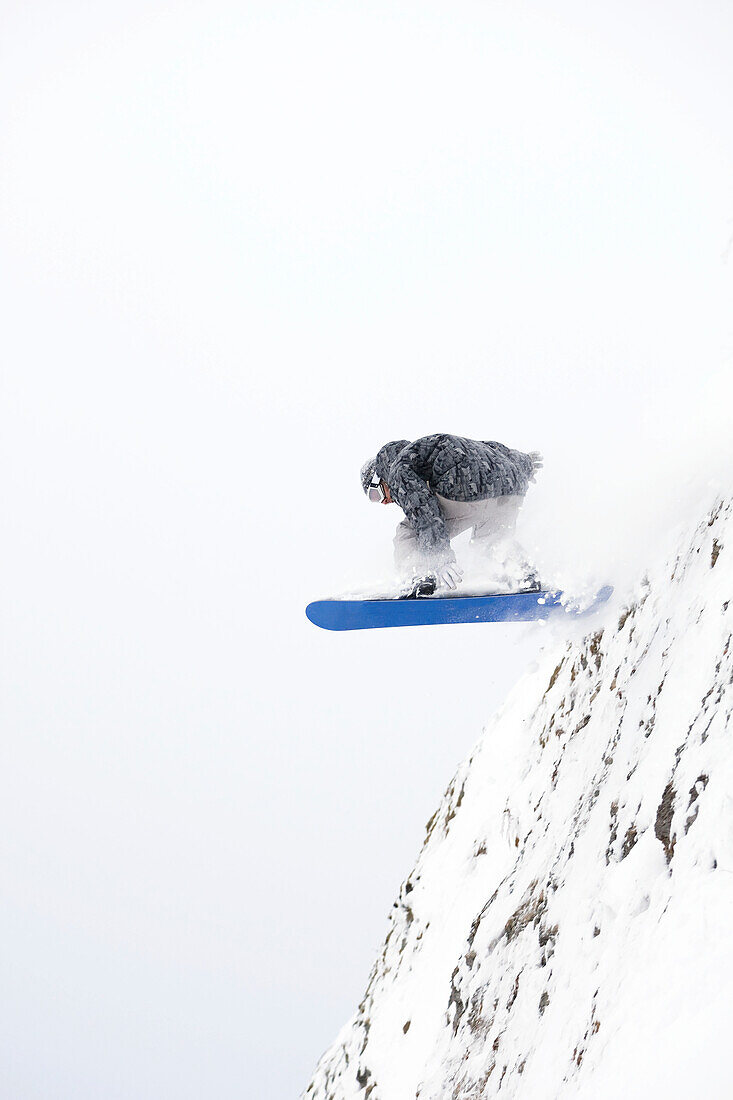 Ein Snowboarder springt von einer Bergklippe ab, Alaska, Vereinigte Staaten von Amerika