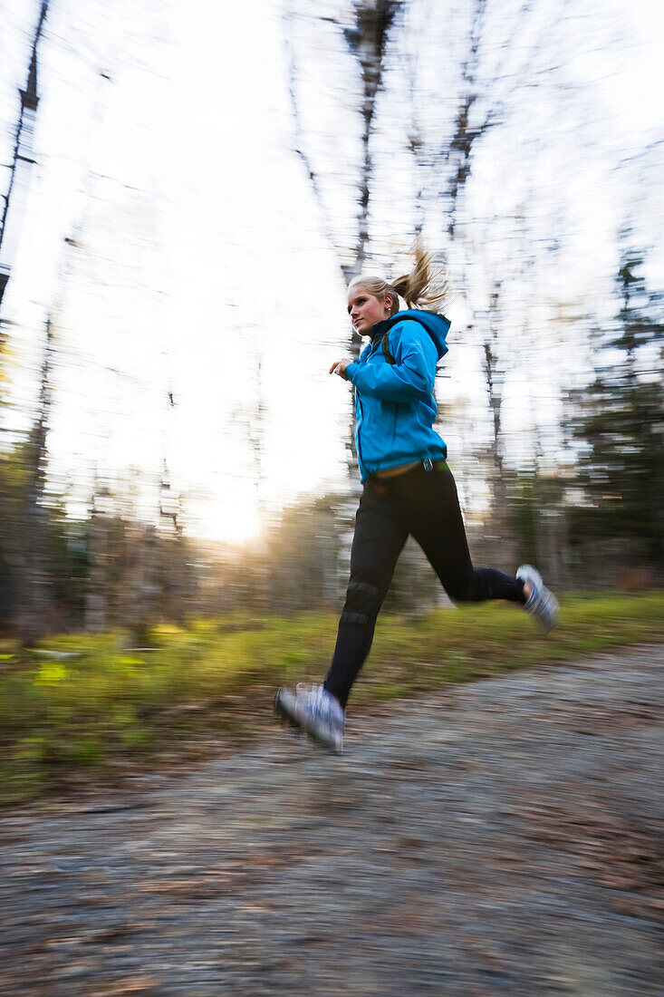 A young woman running on a trail in a forest, Homer, Alaska, United States of America