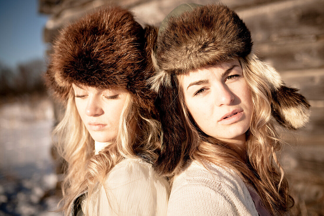 Porträt von zwei Mädchen, die durch eine Blockhütte tragen Pelzmütze, Homer, Alaska, Vereinigte Staaten von Amerika