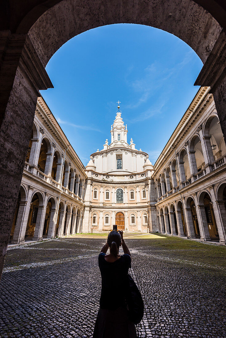 A tourist takes a photo of the inner courtyard of the baroque church Sant'Ivo alla Sapienza, Rome, Latium, Italy
