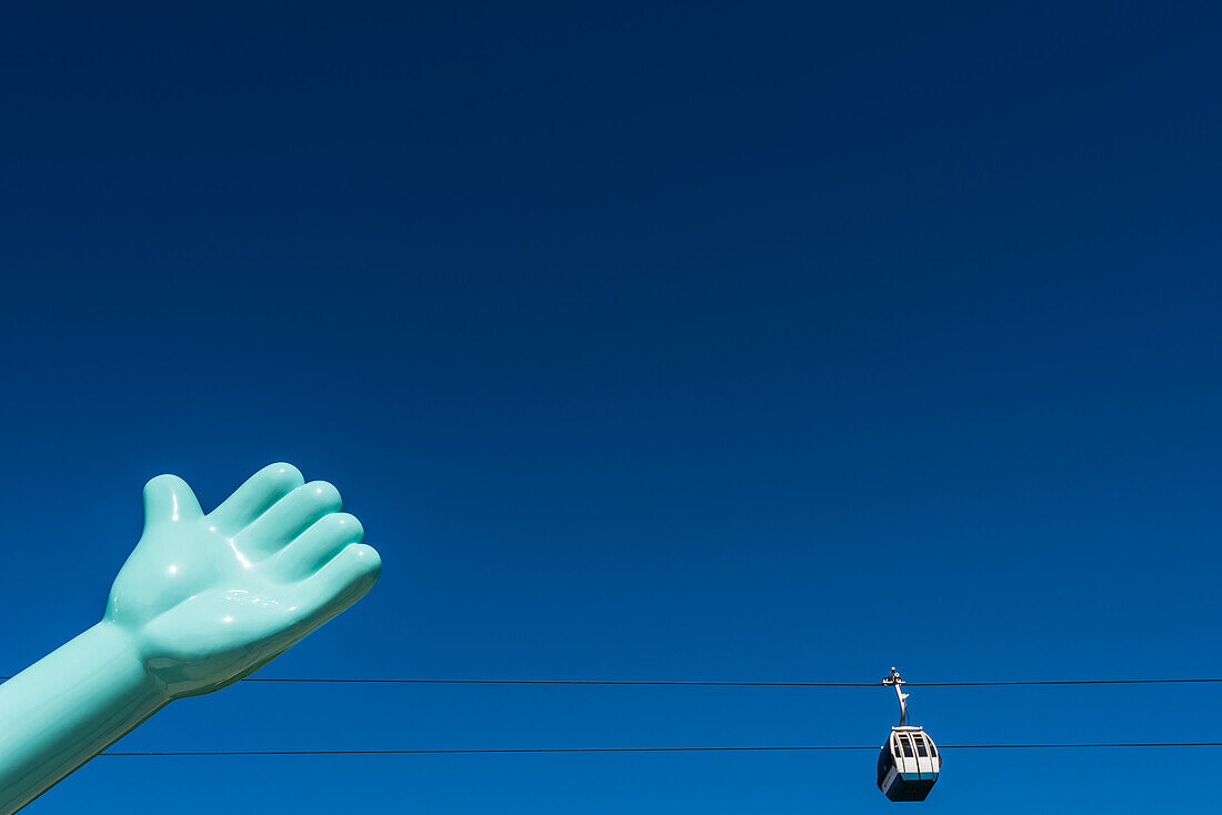 The cable railway Teleférico do Parque das Nações in the Parque das Nações behind a huge hand of a statue, Lisbon, Portugal