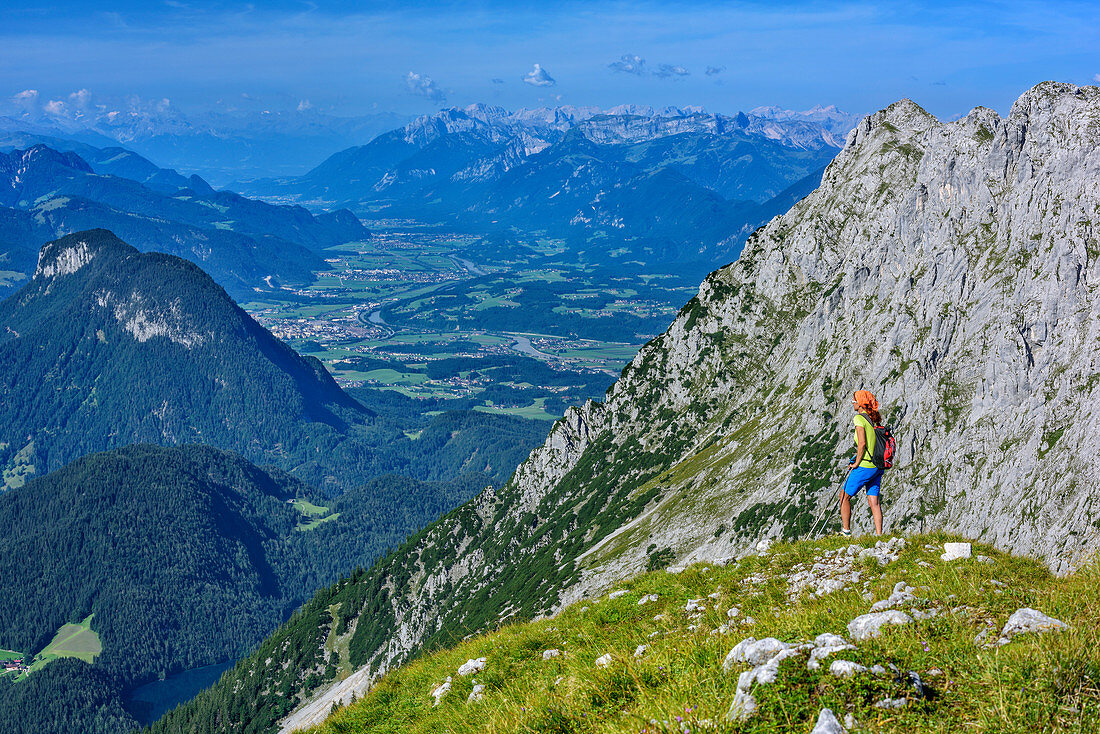 Woman hiking looking towards Poelven, valley Inntal, Rofan range and Karwendel range, from Sonneck, Kaiser range, Tyrol, Austria