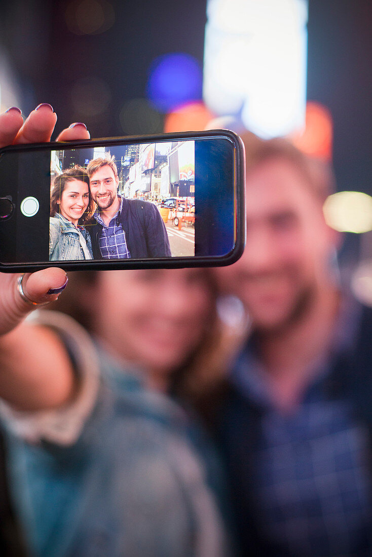 Young couple taking selfie while sightseeing in Times Square, New York City, New York, USA