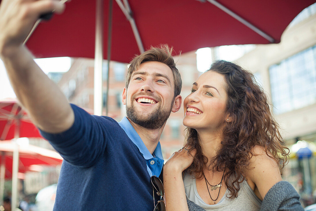 Couple posing for a selfie at an outdoor cafe