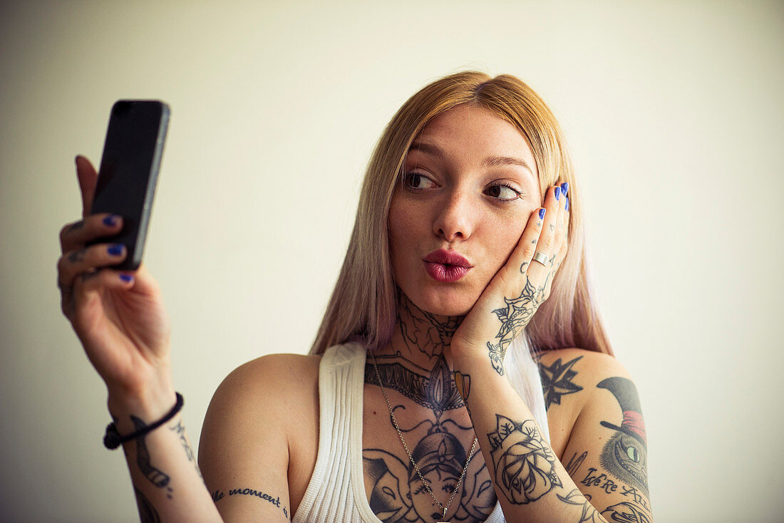 Tätowierte Frau, die selfie mit Smartphone nimmt