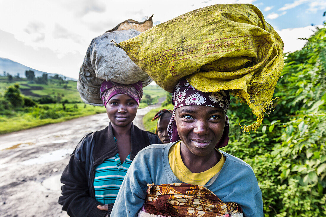 Lokale Frauen, die Waren auf dem Kopf tragen, Virunga National Park, Demokratische Republik Kongo, Afrika