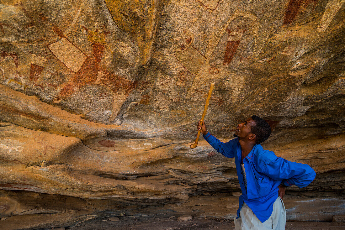 Guide pointing at cave paintings in Lass Geel caves, Somaliland, Somalia, Africa