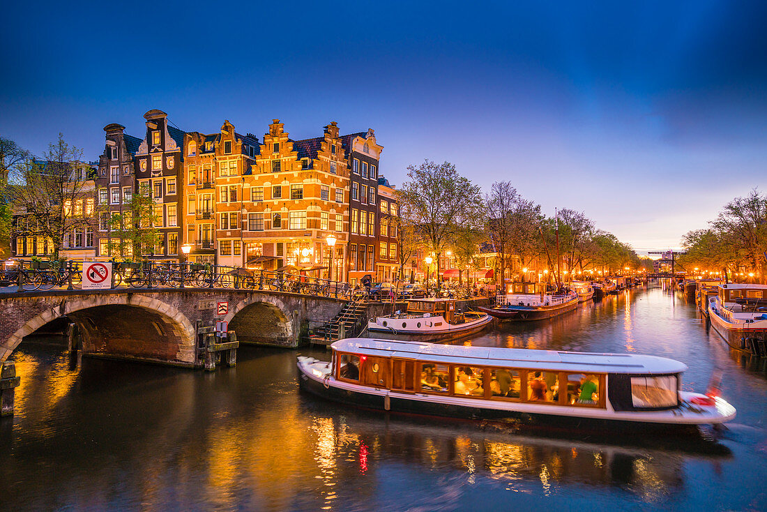 Kanalszene mit Ausflugsschiff in der Abenddämmerung, Amsterdam, Niederlande, Europa