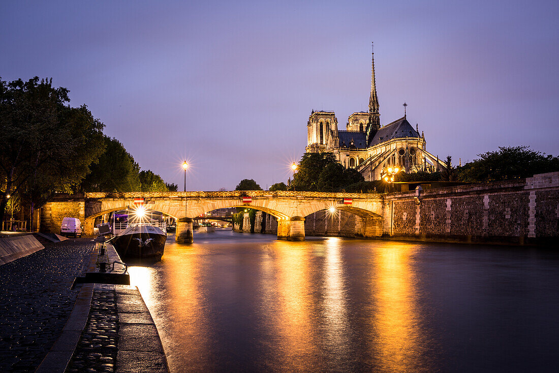 Notre Dame Cathedral and lights reflecting in the River Seine on a wet evening in Paris, France, Europe