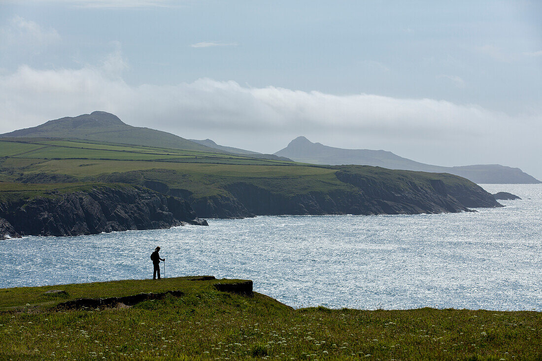 A walker enjoying a moments rest to admire the stunning views from the cliffs along the Pembrokeshire coast path, Wales, United Kingdom, Europe