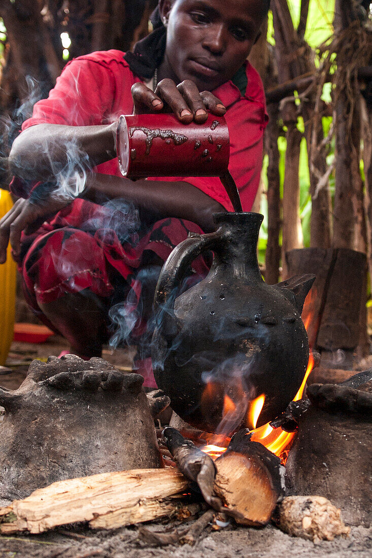 Eine Frau gießt in einem traditionellen äthiopischen Kaffeekanne auf einem offenen Feuer, Äthiopien, Afrika