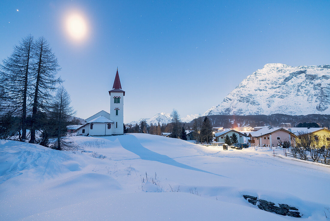 Lichter der Dämmerung auf Chiesa Bianca und alpines Dorf mit Schnee bedeckt, Maloja Pass, Engadin, Graubünden, Schweiz, Europa