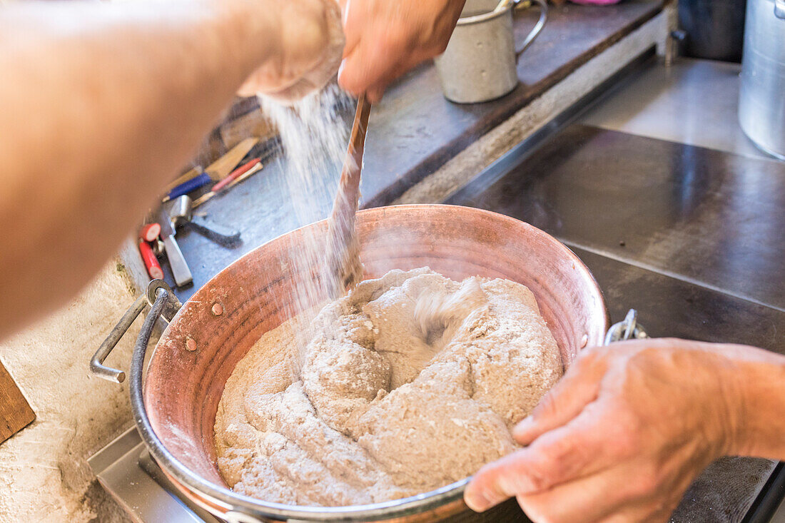 Chef preparing the typical polenta, San Romerio Alp, Brusio, Canton of Graubünden, Poschiavo valley, Switzerland
